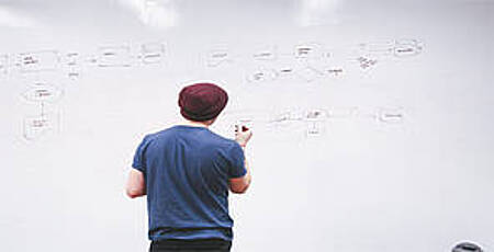 Mann zeichnet Graphen an ein Whiteboard